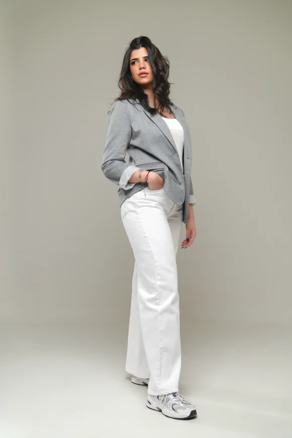 Model wearing a gray blazer, white top, wide-leg white pants, and white sneakers